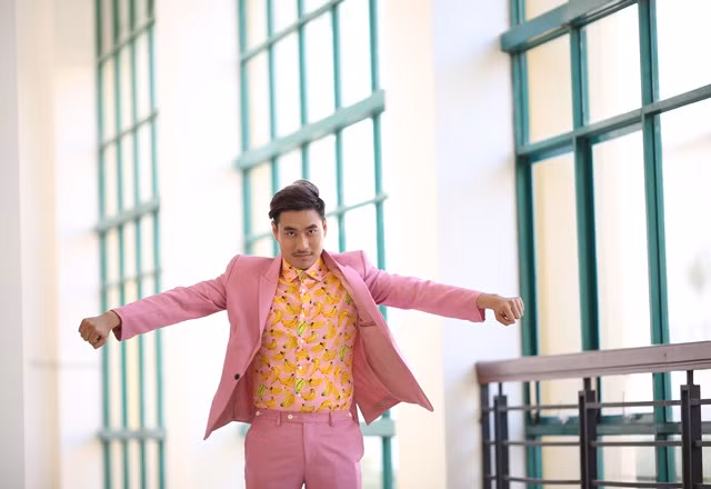 Anh chàng trông khá phong lưu trong bộ vest hồng phối với áo sơ mi chuối vàng.