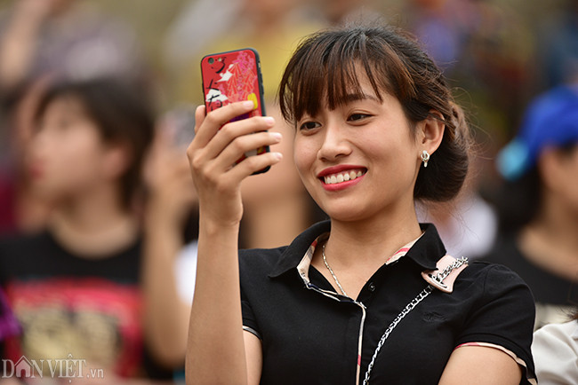 Nhiều khán giả nữ dùng điện thoại quay lại cảnh các đội đua thuyền.