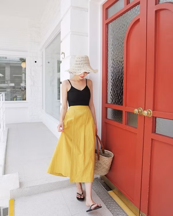 Một chiếc chân váy midi màu vàng mix cùng chiếc áo hai dây đen sẽ mang đến vẻ ngoài đầy trendy mà lại mát mẻ trong mùa hè.