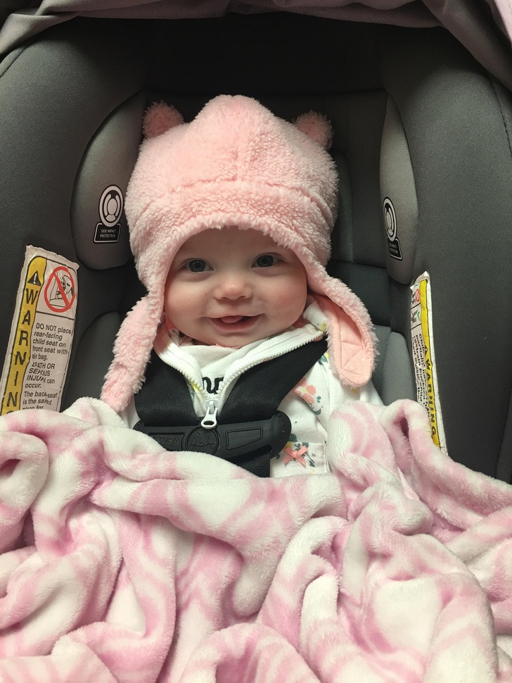 Bé gái xinh xắn cười tươi khi thử chiếc mũ mới.