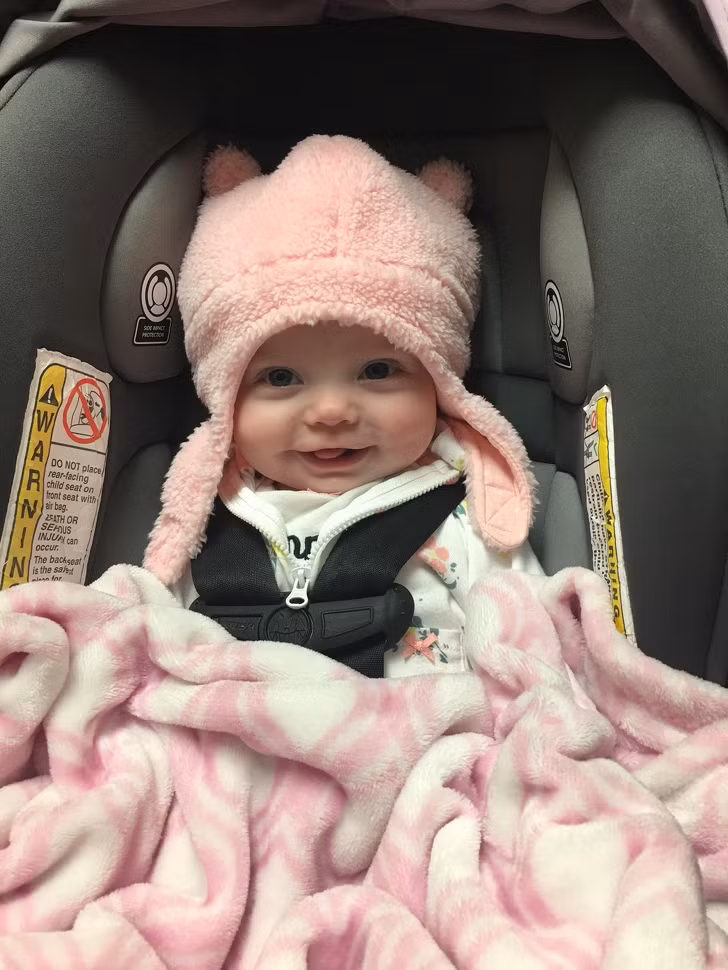 Bé gái xinh xắn cười tươi khi thử chiếc mũ mới.