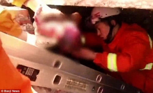 Một lính cứu hỏa chui vào bể chứa lôi đứa bé ra.