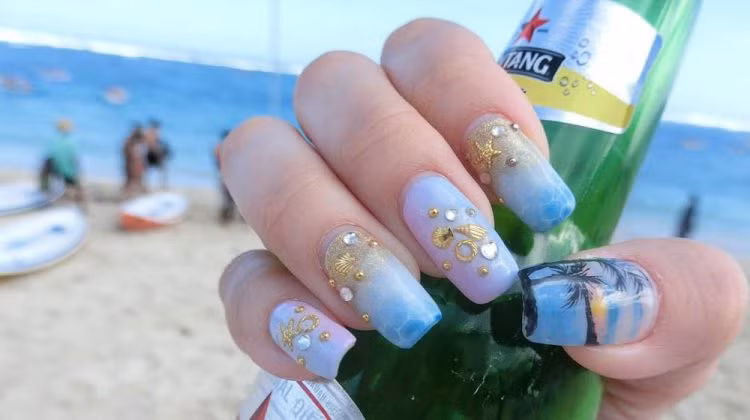 Bên cạnh những vỏ sò màu vàng óng, họa tiết cây dừa cũng khá phổ biến khi vẽ móng tay chủ đề biển cả. giúp bàn tay trông trắng trẻo hơn.