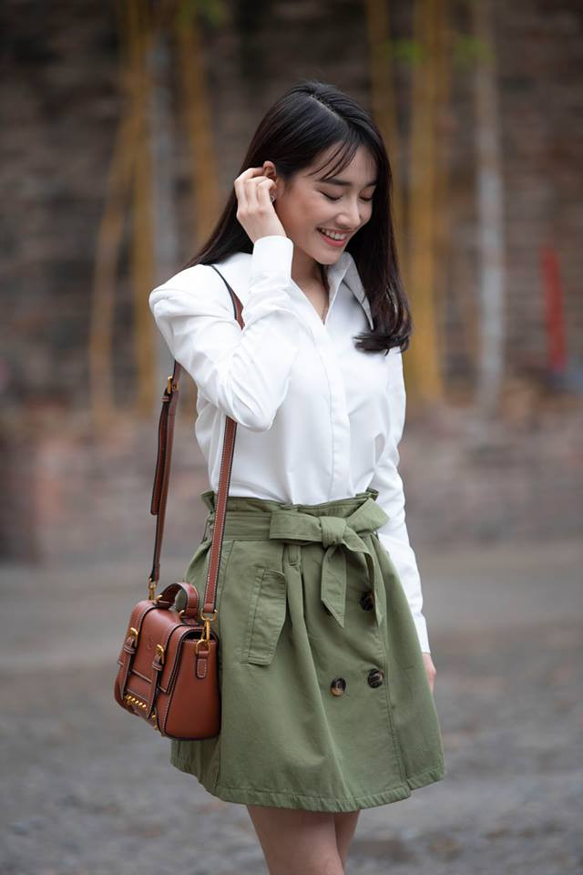 Bà xã Trường Giang chọn trang phục dạo phố đơn giản mà nữ tính với áo sơ mi trắng và váy xanh có thắt nơ điệu đà.