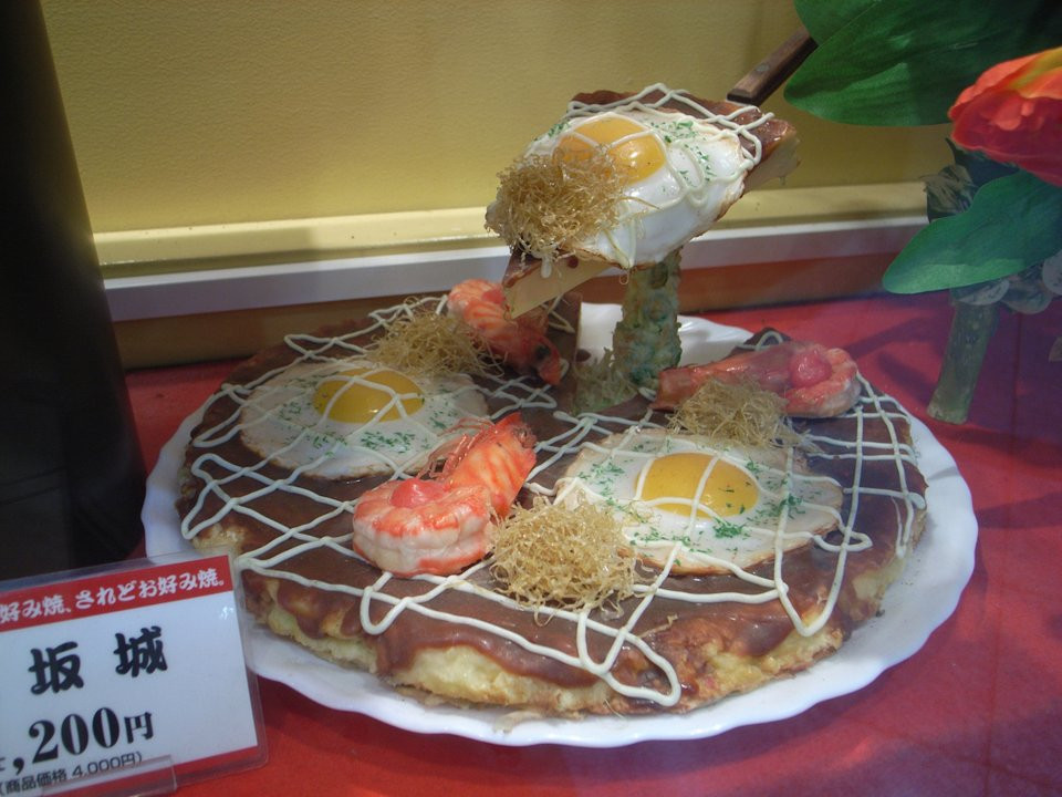 Okonomiyaki là món bánh rán mặn, thơm ngon của Nhật Bản. Chiếc bánh làm từ bột, trứng kết hợp với rau và hải sản. Sau đó rán và rắc thêm chút gừng ngâm, sốt mayonnaise.