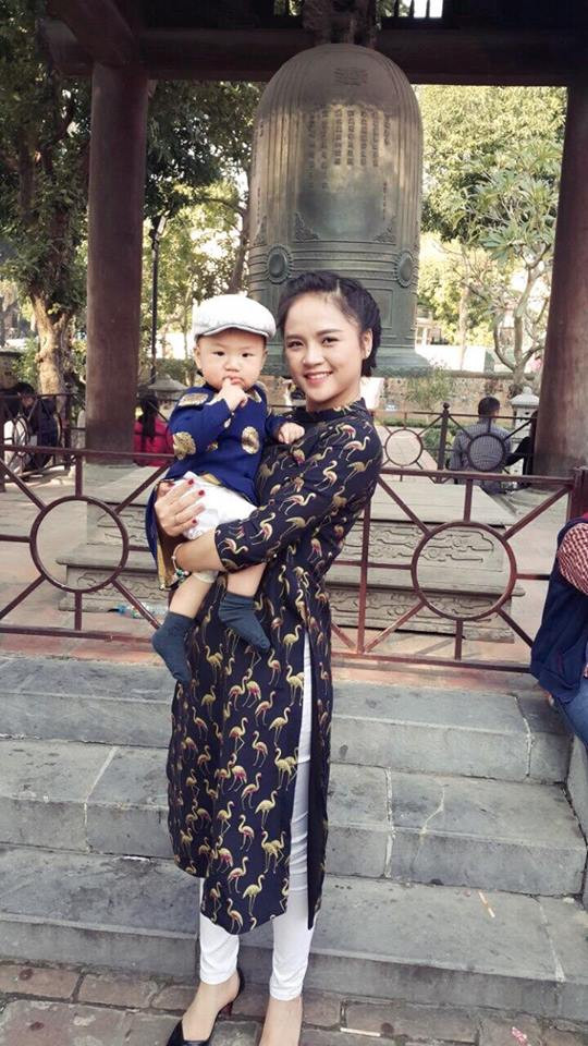 Trong một lần đi chơi cùng con trai, cô mặc áo dài cách tân tối màu phối với quần trắng.