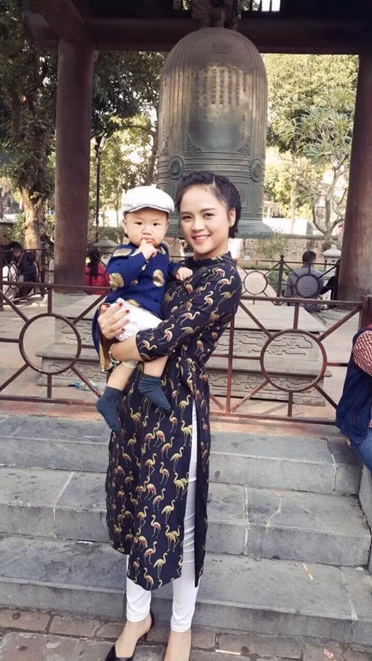 Trong một lần đi chơi cùng con trai, cô mặc áo dài cách tân tối màu phối với quần trắng.