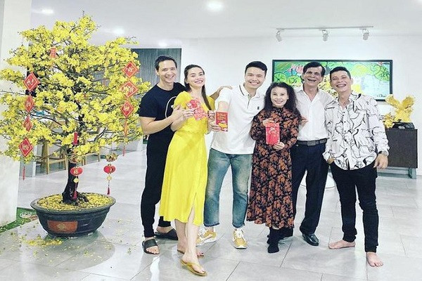 Hồ Ngọc Hà đón Tết cùng cha mẹ và bạn trai Kim Lý. Nữ ca sĩ mặc bộ váy vàng trùng tông màu với hoa mai và giơ cao bao lì xì đầy vui vẻ. "Nụ cười xuân của cả nhà", cô chú thích.