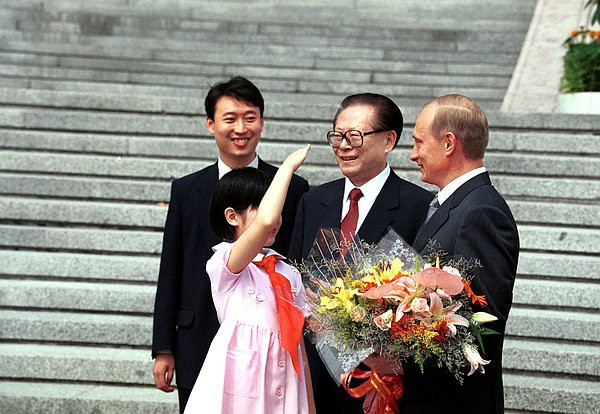 Tháng 7/2000, ông Putin có chuyến thăm chính thức Trung Quốc. Buổi lễ long trọng đón tiếp tổng thống Nga đã diễn ra trên quảng trường Thiên An Môn ở trung tâm thành phố Bắc Kinh, Trung Quốc. Trong ảnh, em học sinh Trung Quốc quàng khăn đỏ tặng hoa và thực hiện động tác chào Tổng thống Putin, đứng cạnh là Chủ tịch Trung Quốc Giang Trạch Dân.