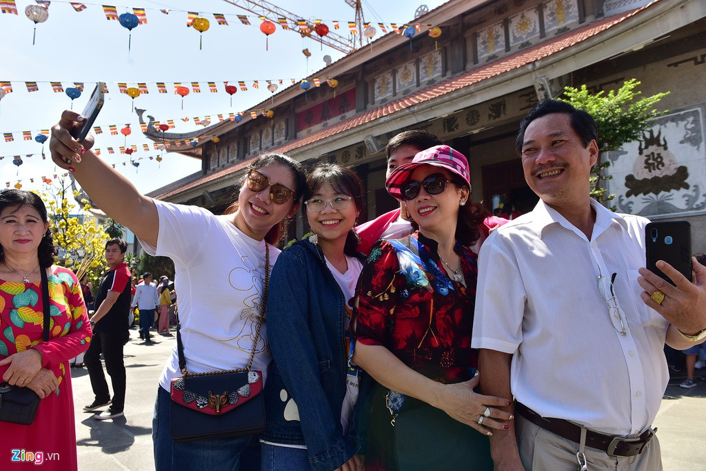 Gia đình chị Đinh Thị Hồng Châu (quận 10) cùng chụp ảnh lưu niệm trong ngày đầu năm mới tại chùa Vĩnh Nghiêm sau khi vào cầu khấn trong điện chính. "Cứ sáng mùng 1 Tết hàng năm, sau khi cúng tổ tiên xong, gia đình chúng tôi đều tới chùa này để cầu an năm mới gặp nhiều may mắn trước khi đi chúc Tết bà con, bạn bè", chị Châu cho hay.