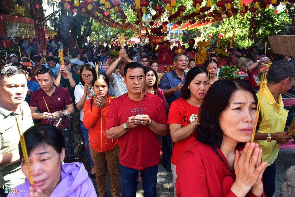 Các lư hương đặt ngoài khuôn viên chùa chật kín người đứng thắp hương cầu an năm mới.