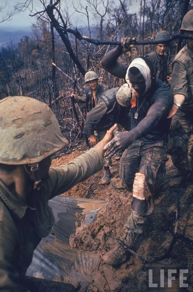 Một binh sĩ bị thương được đồng đội hỗ trợ khi di chuyển đến địa điểm di tản bằng trực thăng. Ảnh: Larry Burrow/Life.