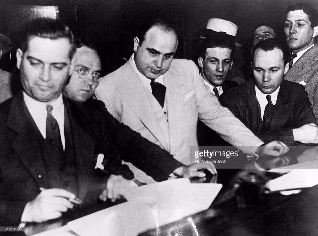 Trùm mafia Al Capone ký giấy tại ngoại sau khi bị bắt giữ để điều tra về tội trốn thuế ở Chicago năm 1931. Ảnh: Getty.