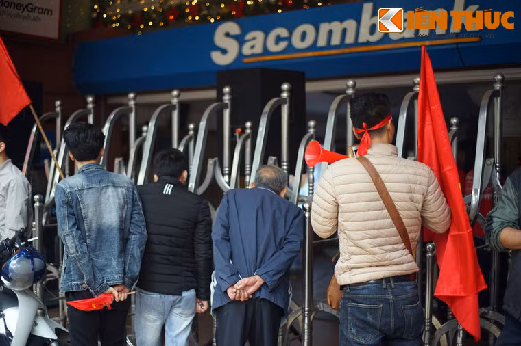 Người qua đường ghé mắt qua hàng rào để "xem ké" trận U23 Việt Nam - U23 Uzbekistan từ chiếc TV đặt ở tầng 1 chi nhánh ngân hàng Sacombank trên phố Hàng Bài.