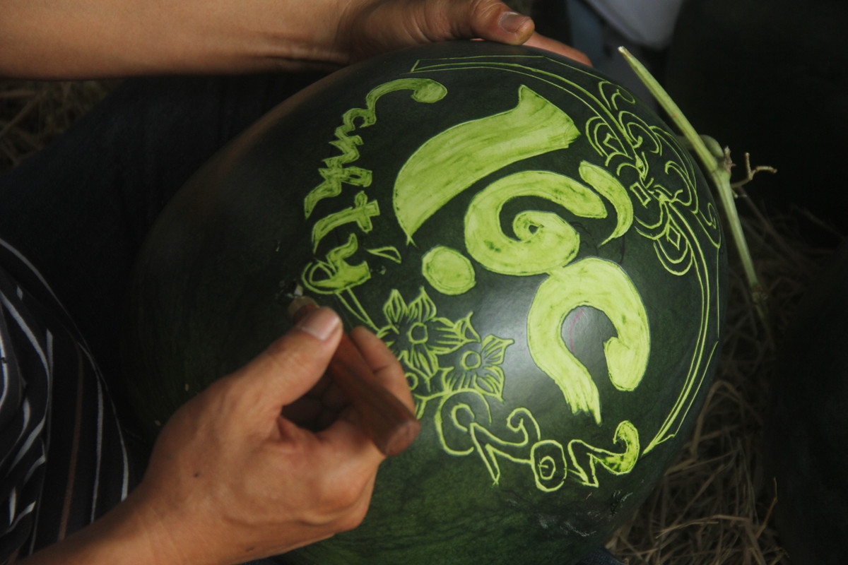  Để làm ra một tác phẩm độc đáo từ quả dưa hấu, nghệ nhân phải thực hiện 3 công đoạn. Đầu tiên vẽ phác thảo, sau đó tỉa bằng dao, cuối cùng là gọt, khắc chữ và hình lên quả dưa. 