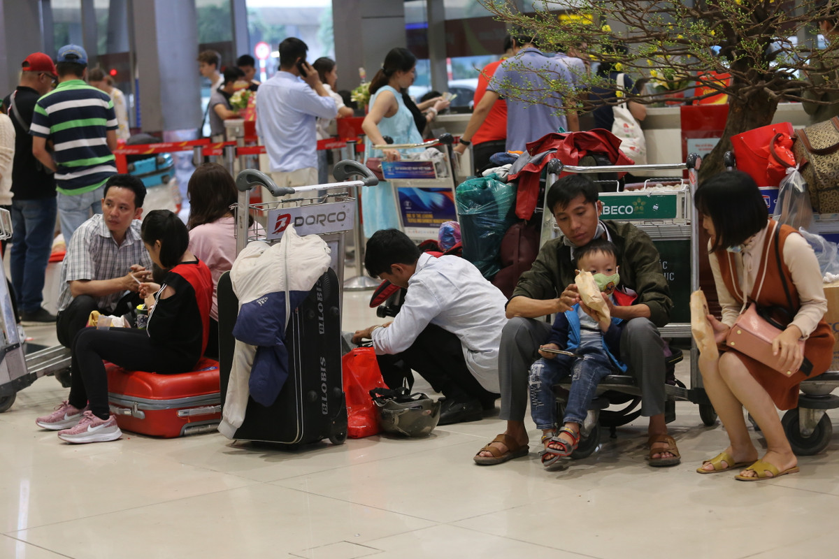Người lớn, trẻ nhỏ ngồi la liệt khắp sảnh sân bay để chờ làm thủ tục.