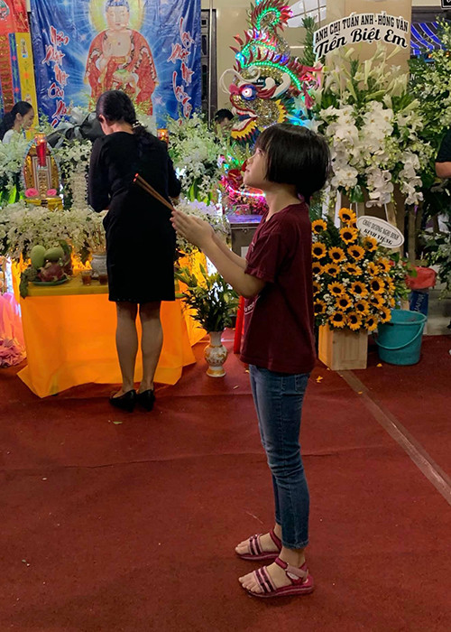 Bé Nguyệt Cát thắp nén nhang cho nghệ sĩ Anh Vũ. Ảnh: FBNV