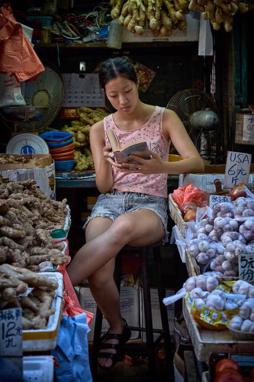 Cô gái trẻ chăm chú đọc sách ở quầy bán hàng trên phố Reclamation Street, Mongkok.