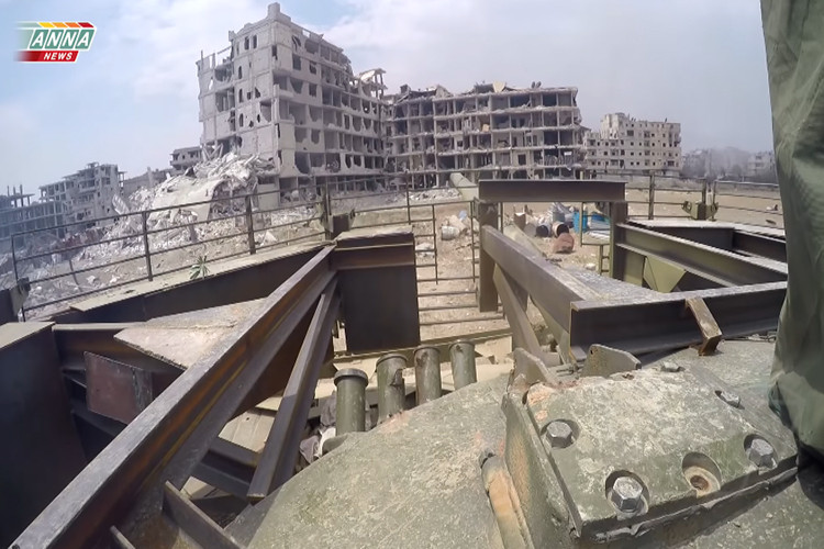 Trong ảnh là xe tăng T-72 Shafrah với thiết kế giáp lồng bảo vệ đặc trưng tiến vào một vị trí phòng thủ của IS bên trong Yarmuk. Nguồn ảnh: ANNA News.