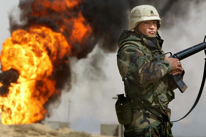 Hạ sĩ quan lục quân Mỹ Robert Dominguez đứng gác gần một giếng dầu đang cháy ở Rumayla, Iraq, vào ngày 27/3/2003. Quân Iraq khi rút lui đã đốt cháy các giếng dầu như thế này (ảnh: Getty).