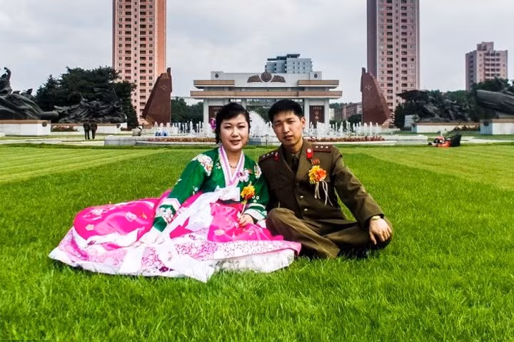 Cặp đôi mới cưới, với chú rể là một quân nhân, chụp ảnh trên thảm cỏ gần một đài phun nước ở Bình Nhưỡng.