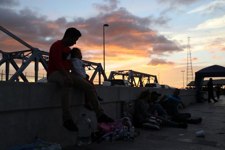 Ông bố Elder Diaz người Honduras cùng cô con gái 3 tuổi Glsela giữa những người đang "chầu chực" trên cây cầu ở biên giới Mexico.