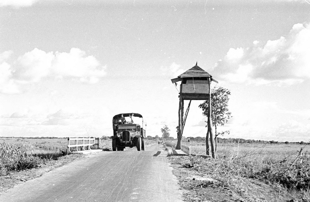 Chiếc xe tải đi qua một tháp canh dạng nhà sàn. Ảnh: Harrison Forman.