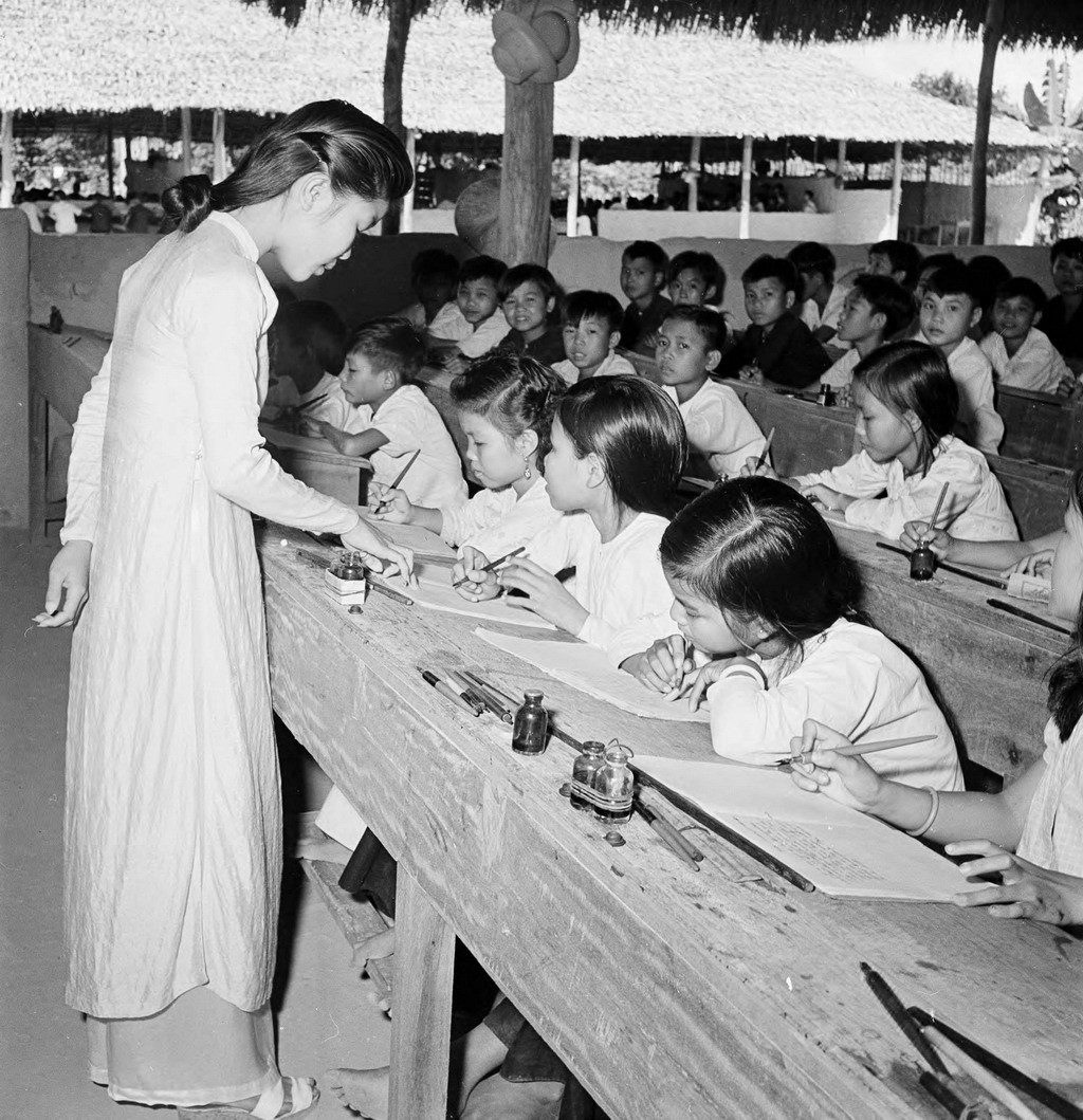 Nữ giáo viên trẻ hướng dẫn cho học sinh làm bài. Ảnh: Harrison Forman.