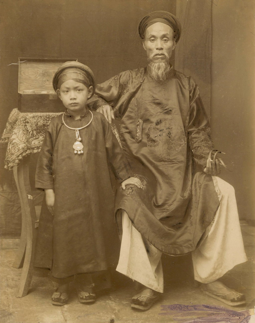 Một thầy thuốc ở Hà Nội xưa với móng tay để dài. Cậu bé bên cạnh có lẽ là con trai. Ảnh tư liệu.