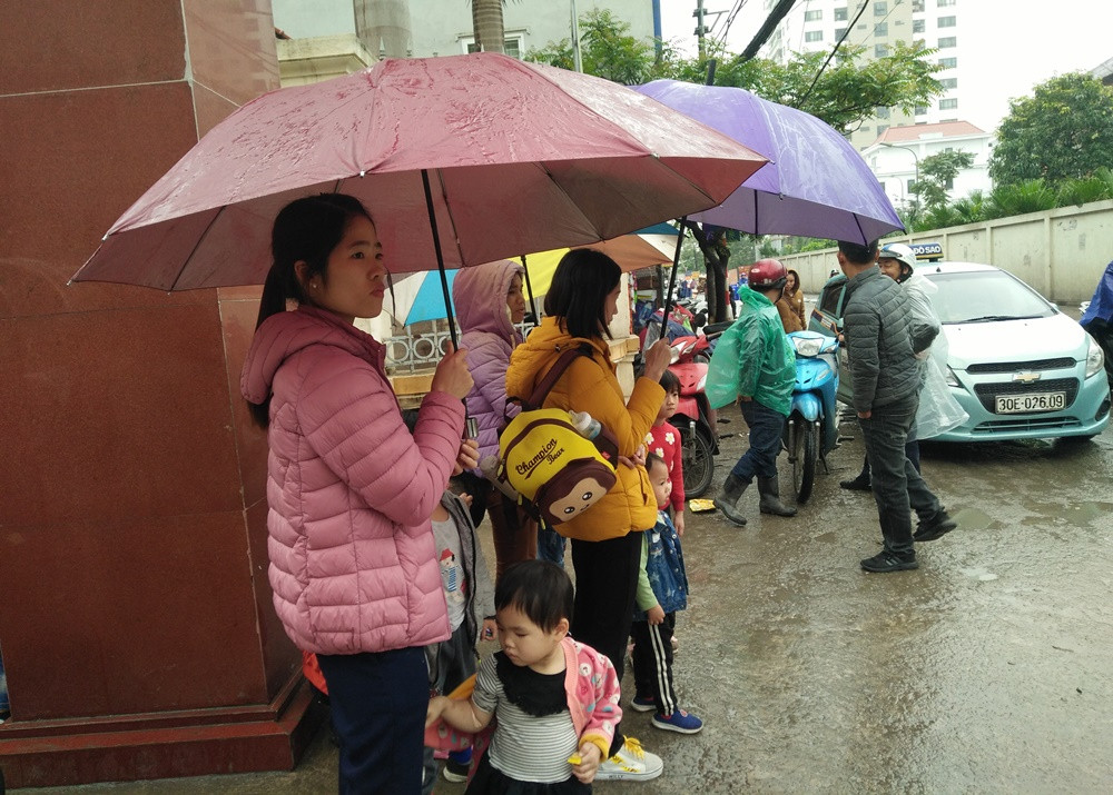 Phụ huynh chịu mưa rét để đưa con đi khám, ai cũng mong nhận được kết quả tốt.