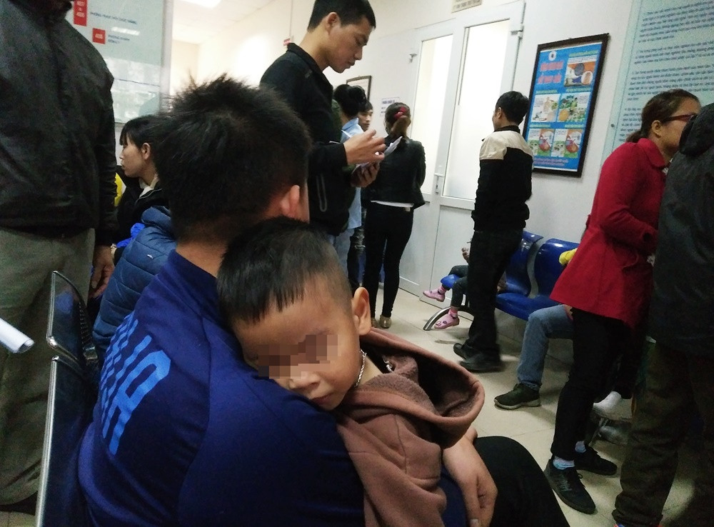 Các em nhỏ mệt mỏi, gục ngủ trên vai phụ huynh vì vừa phải di chuyển một quãng đường xa lên Hà Nội khám bệnh.