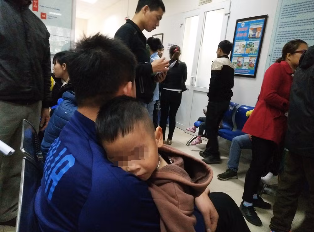 Các em nhỏ mệt mỏi, gục ngủ trên vai phụ huynh vì vừa phải di chuyển một quãng đường xa lên Hà Nội khám bệnh.