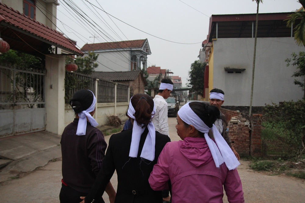 Trong khi đó, phía trong thôn Trung Nguyên, từng tốp người đầu đội khăn tang trắng lần lượt thay nhau đến gia đình 7 nạn nhân tử vong để thắp hương kính viếng.