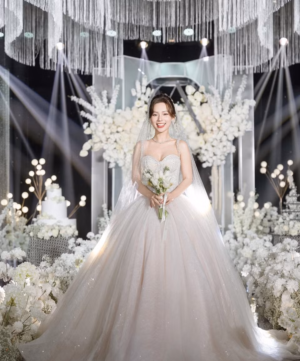 Trang phục có kiểu dáng xòe rộng với chất liệu voan cao cấp, mềm mại giúp cô dâu dễ dàng di chuyển. Điểm nhấn của trang phục là hàng ngàn viên pha lê Swarovski được đính kết tỉ mỉ trên phần thân váy.