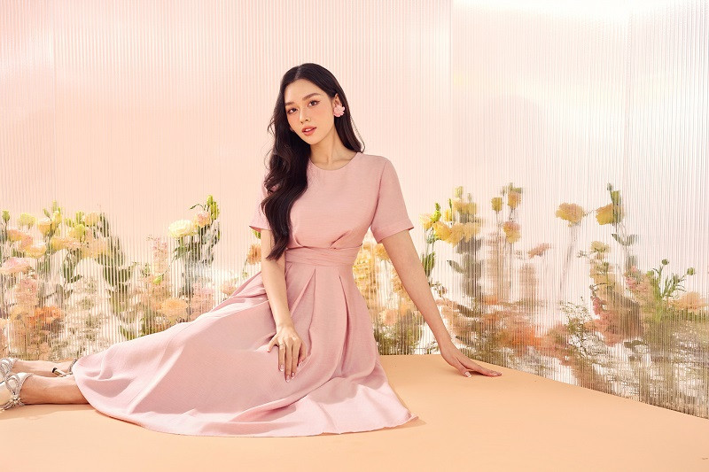 Một thiết kế đầm xếp ly dáng xòe, tạo điểm nhấn ở vòng eo bằng chi tiết xếp nếp vải thủ công kết hợp với sắc hồng đào xinh xắn giúp cô nàng trông như một nàng công chúa bước ra từ chuyện cổ tích.