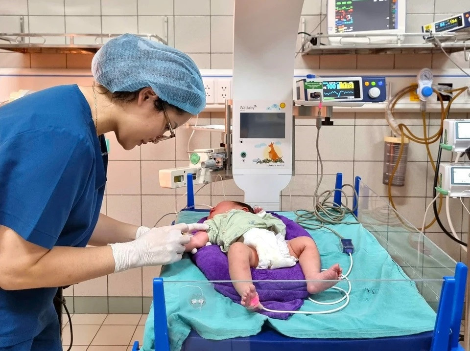 Ánh mắt yêu thương, ân cần của nữ điều dưỡng dành cho em bé sơ sinh đang được chăm sóc tại phòng hồi sức.