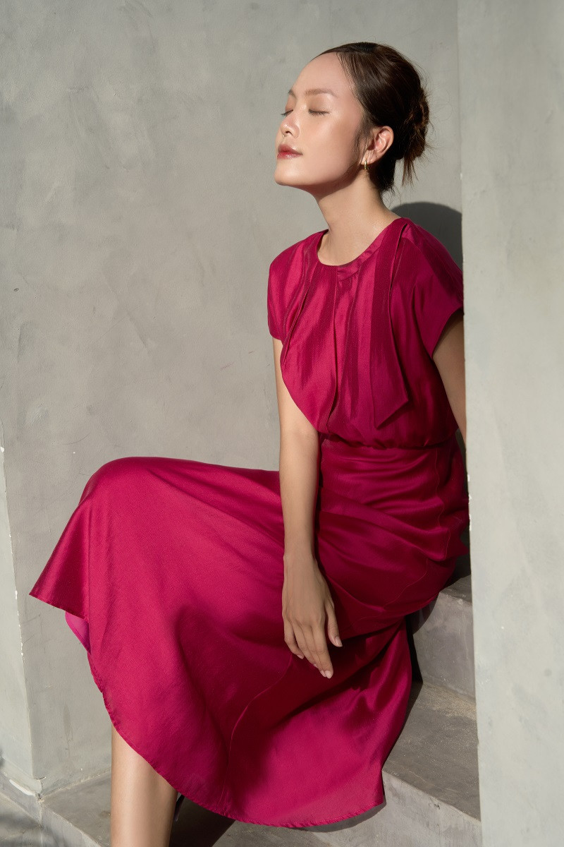 Đầm dáng xòe nhẹ cùng chiều dài midi, được thiết kế theo phong cách cổ điển, tinh tế nhưng vẫn đủ nổi bật qua các điểm nhấn xếp nếp phần chân cổ và thân trước.