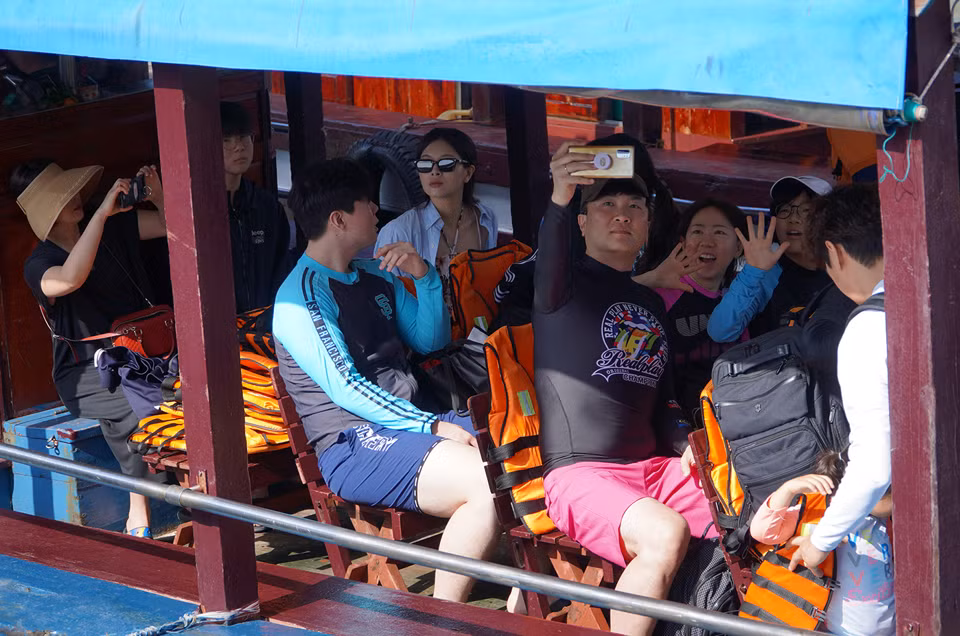 Một gia đình người Hàn Quốc chụp ảnh kỷ niệm khi lên tàu gỗ khám phá Vịnh Nha Trang.