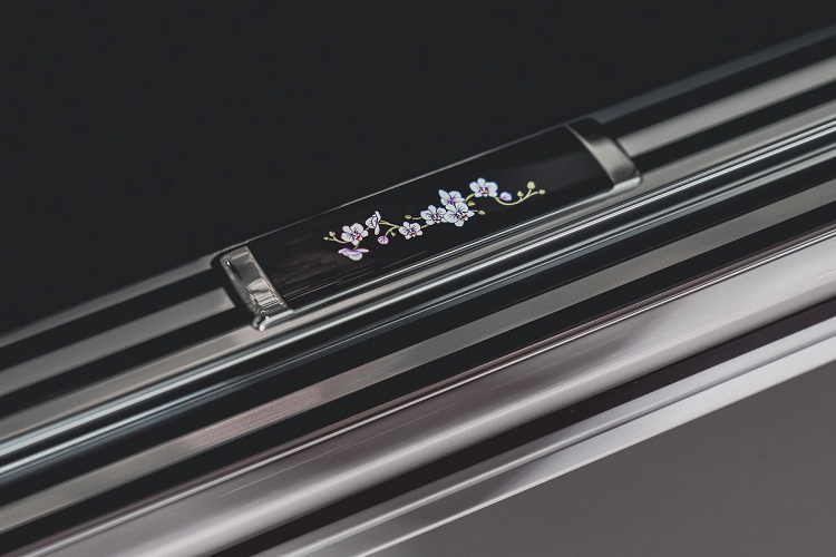 Vì đây là một chiếc Phantom duy nhất nên quá trình cá nhân hóa không chỉ dừng lại ở ở khu vực táp lô. Hai chi tiết đặc biệt khác được nhà thiết kế Yohan Benchetrit của Rolls-Royce Bespoke tạo nên là bàn ăn và bệ bước chân mang họa tiết phong lan trên lớp gỗ ốp màu đen piano black.