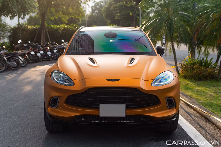 Aston Martin DBX trong bài sở hữu lớp sơn màu vàng cam nhám có tên Satin Golden Saffron. Màu sơn này nằm trong mục cá nhân hoá của bộ phận Q của Aston Martin. Đầu xe sỡ hữu lưới tản nhiệt ‘DB’ cỡ lớn đặc trưng. Cụm đèn chiếu sáng LED hình oval đơn giản, hệ thống đèn định vị ban ngày của xe được đặt bao quanh một hốc gió.