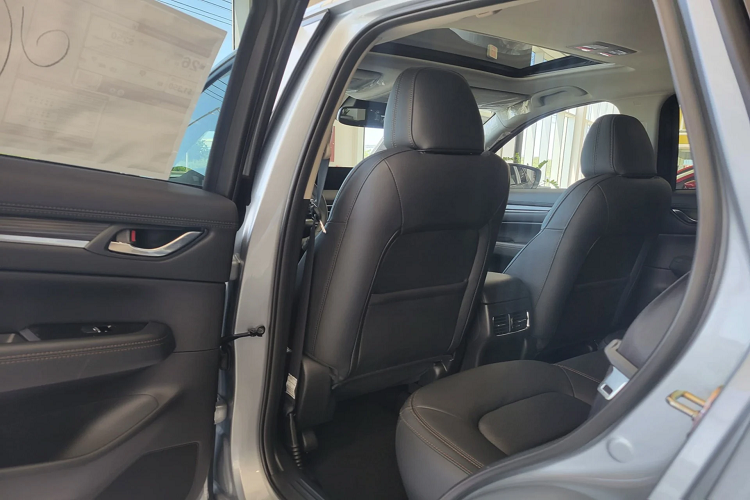 Ở thị trường khác như Mỹ, nội thất Mazda CX-5 2022 (tùy phiên bản) được trang trí thêm các họa tiết vân gỗ trên táp-pi cửa và bảng điều khiển trung tâm, đi kèm với các trang bị tiện nghi như sạc điện thoại không đây.