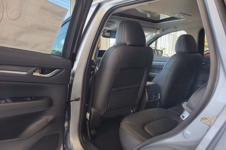 Ở thị trường khác như Mỹ, nội thất Mazda CX-5 2022 (tùy phiên bản) được trang trí thêm các họa tiết vân gỗ trên táp-pi cửa và bảng điều khiển trung tâm, đi kèm với các trang bị tiện nghi như sạc điện thoại không đây.