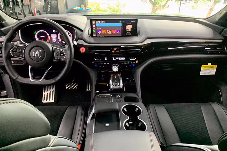 Bên trong cabin, Acura MDX 2022 bản A-Spec có hệ thống ghế ngồi thể thao bọc da Milano đục lỗ, bảng táp-lô ốp gỗ mun, vô-lăng đáy phẳng có logo, lẫy chuyển số và bàn đạp kim loại...
