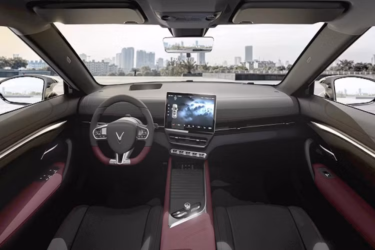 Hai bên hông xe VinFast VF7 có thiết kế khá ấn tượng với đường gân nổi kết hợp cùng các vùng khoét sâu, tạo cho xe vẻ mạnh mẽ và cứng cáp, nắm cửa được thiết kế chìm vừa giúp tăng tính khí động học, vừa mang đến sự liền mạch và gãy gọn. Ngay bên dưới cột a ở phần đầu xe là vị trí cổng sạc pin cho xe. Bước lùi về phía sau, phong cách thiết kế dải đèn LED dải ở đầu xe tiếp tục được áp dụng ở đèn phanh. Phần đèn phanh tích hợp xi-nhan dạng LED được bố trí hai bên logo chữ V, kéo dài sang đến hông xe. Bên dưới là hai hốc bố trí khe thoát gió. Vị trí bắt biển số phía sau được bố trí cao phía trên cản sốc sau trên nền đen khá nổi bật.