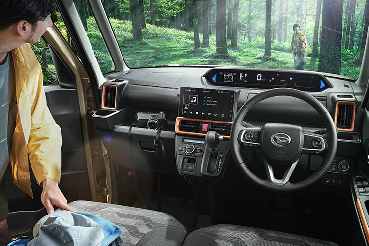 Chưa hết, Daihatsu Tanto FunCross 2023 còn được trang bị ghế bọc nỉ màu rằn ri, lưng ghế sau và sàn khoang hành lý chống thấm nước. Trước mặt người lái xuất hiện vô lăng 3 chấu, tích hợp phím chức năng và bảng đồng hồ kỹ thuật số khá dài, nằm cao trên mặt táp-lô. Bên cạnh đó là màn hình thông tin giải trí dạng cảm ứng 9 inch và cụm điều khiển trung tâm đặt khá cao.