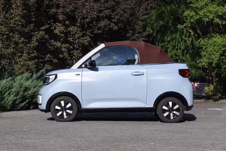 Ngay cả cản trước của mẫu xe mui trần này cũng khác biệt so với Wuling Hongguang Mini EV thông thường. Bên sườn, Wuling Hongguang Mini EV Cabrio 2023 được trang bị bộ vành với thiết kế riêng. Vành la-zăng của xe có thiết kế 6 chấu và được sơn 2 màu. Cột A của mẫu xe mui trần này sẽ được sơn màu xám nhám trong khi mui nỉ có 2 tùy chọn màu là đen tiêu chuẩn và đỏ rượu tùy chọn.