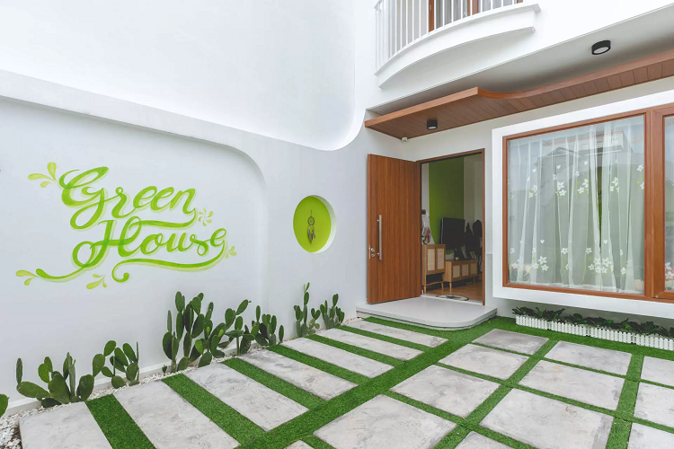 Khoảng sân này cũng là nơi để xe ô tô của gia đình. Khung cửa sổ lớn giúp bên trong nhà luôn sáng, tiết kiệm điện năng vào ban ngày. Phòng khách mở rộng với điểm nhấn chính là khu vực tường được sơn xanh tạo vòm cong mềm mại.