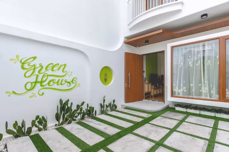 Khoảng sân này cũng là nơi để xe ô tô của gia đình. Khung cửa sổ lớn giúp bên trong nhà luôn sáng, tiết kiệm điện năng vào ban ngày. Phòng khách mở rộng với điểm nhấn chính là khu vực tường được sơn xanh tạo vòm cong mềm mại.