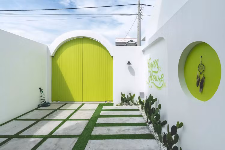 Sân trước nhà lát đá to bản và trồng cỏ xen kẽ, lọc bụi, tránh trơn trượt khi trời mưa. Cánh cổng sáng màu là điểm nhấn cho khu sân vườn. Hàng cây xương rồng phù hợp khí hậu địa phương, dễ trồng, dễ chăm sóc và đẹp mắt. 