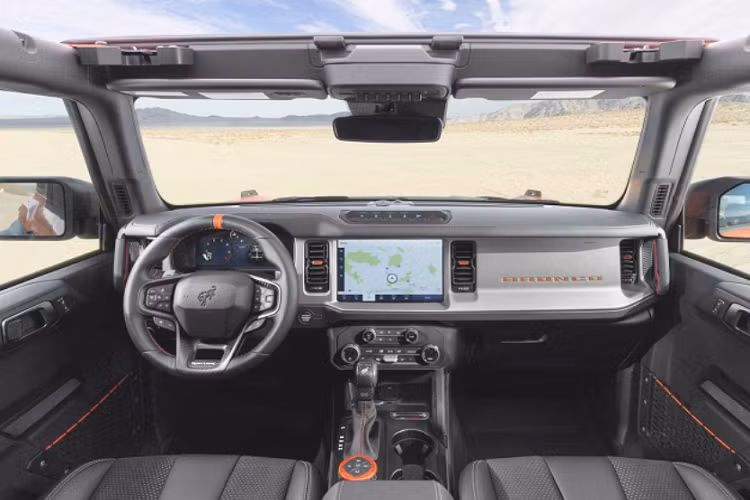 Các thay đổi trực quan trên Bronco Raptor bao gồm bộ mâm 17 inch đi kèm lốp địa hình BFGoodrich K02, vòm bánh mở rộng sơn đen, nắp capo và lưới tản nhiệt Raptor, cản trước Ford Performance tích hợp tời kéo, phối màu cam sáng nổi bật, cụm công cụ kỹ thuật số 12 inch với giao diện Raptor, ghế ngồi Ford Performance,...